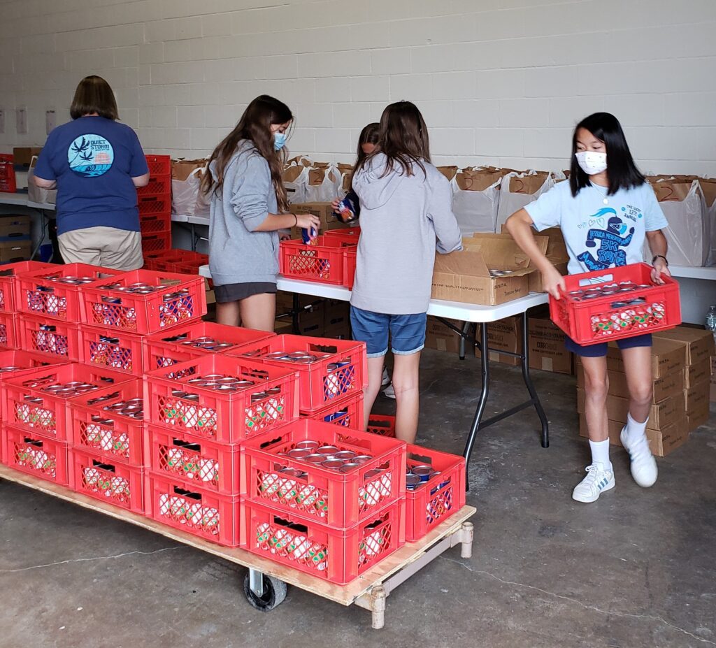 2021Aug-ImmacConcepWorkCamp2 Four members of Youth Work Camp sorting canned goods