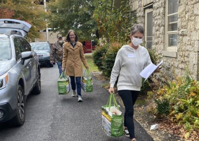 individuals walking with grocery bags and cars driving up to deliver food donations outside Trinity Episcopal Church